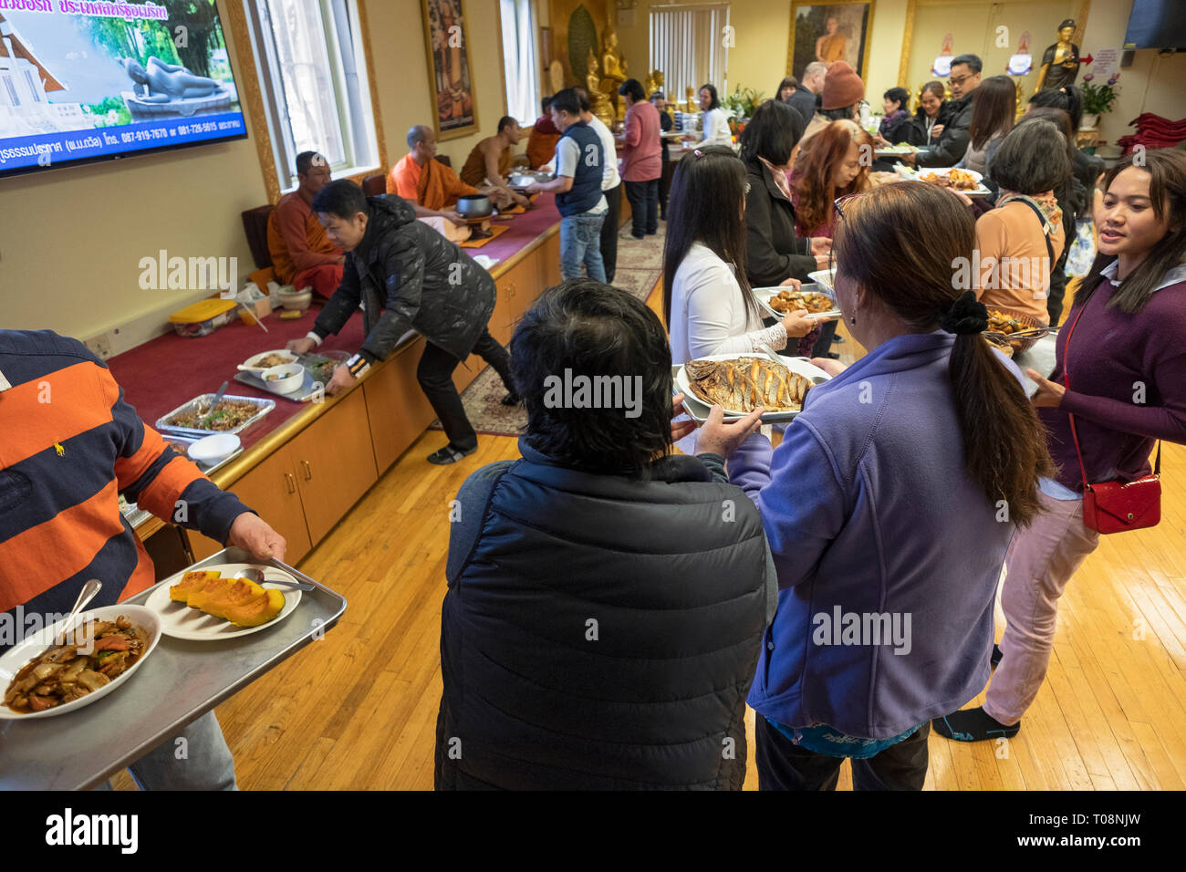 Anbeter in einem buddhistischen Tempel Form einer Montagelinie zu dienen Essen, besonders für ihre Mönche vorbereitet. In Elmhurst, Queens, New York City. Stockfoto