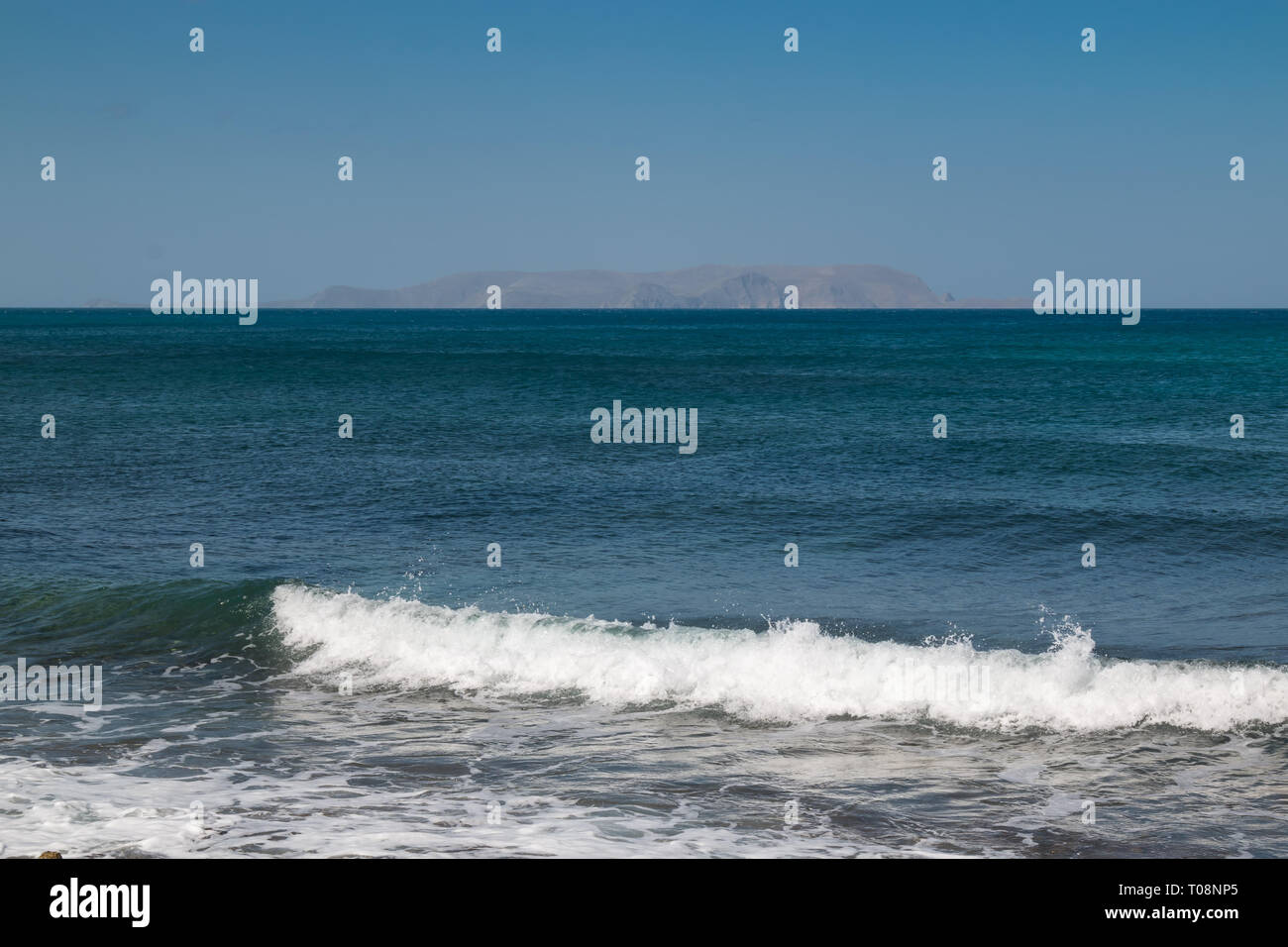 Marine: Türkis im ruhigen Wasser des Mittelmeers mit einer kleinen Küste Welle. Ganz im Hintergrund die Berge am Horizont. Blue Sky. Gouves, Kreta Stockfoto