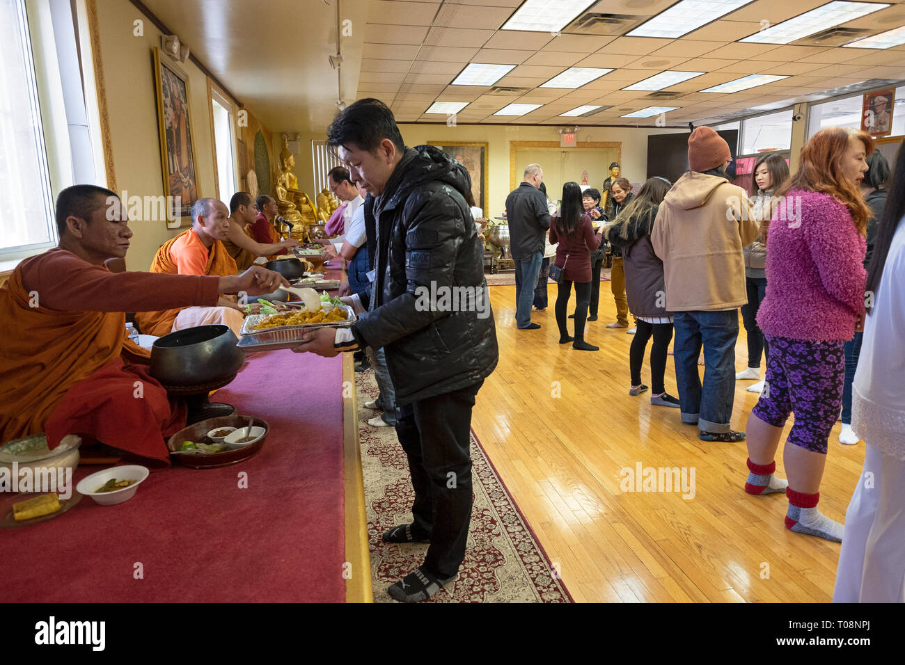 Anbeter in einem buddhistischen Tempel Form einer Montagelinie zu dienen Essen, besonders für ihre Mönche vorbereitet. In Elmhurst, Queens, New York City. Stockfoto