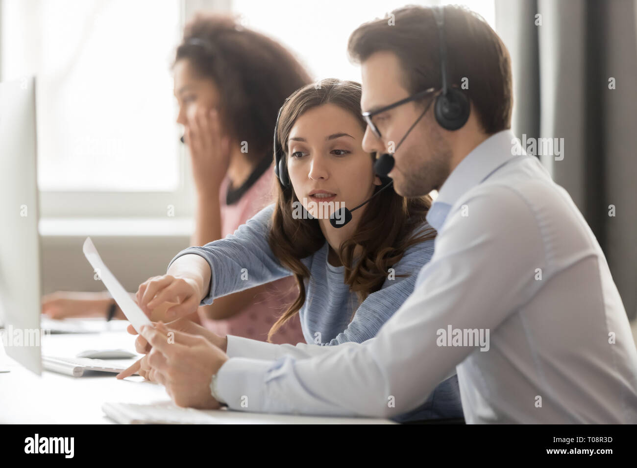 Call Center Agenten in Headsets diskutieren Papiere helfen am Arbeitsplatz Stockfoto