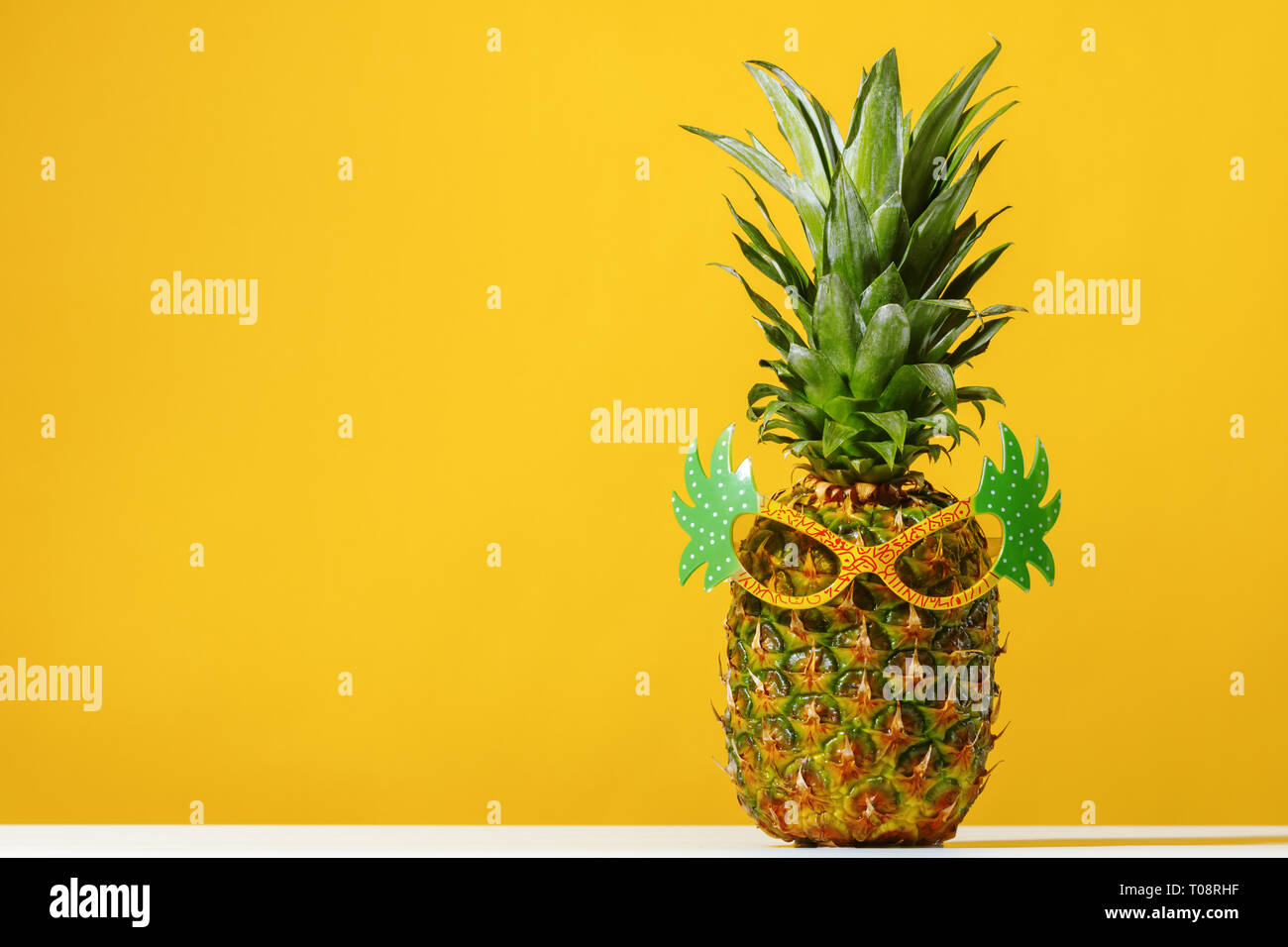 Ananas trägt Sonnenbrille auf gelbem Hintergrund Stockfoto