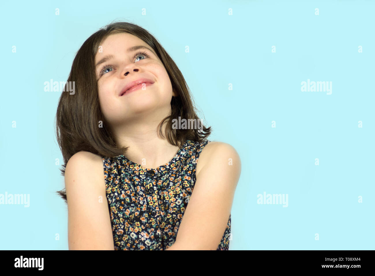 Kleines Mädchen mit blauen Augen und kurze Haare Suchen auf blauem Hintergrund Stockfoto