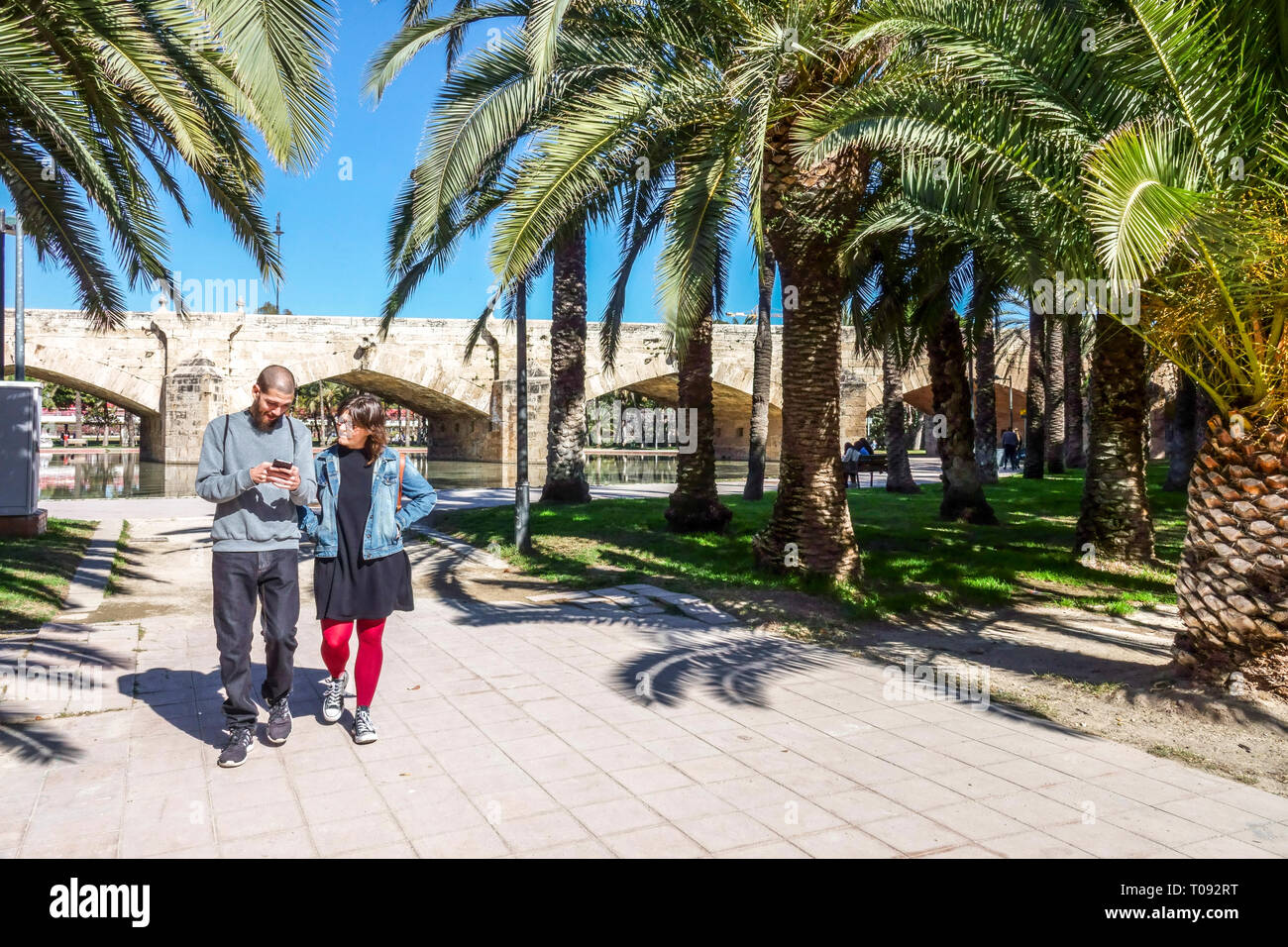 Ein Paar aus Valencia, das unter Palmen in den Valencia Turia Gardens spaziert, Spanien, in einem Garten mit Palmen spaziert Stockfoto