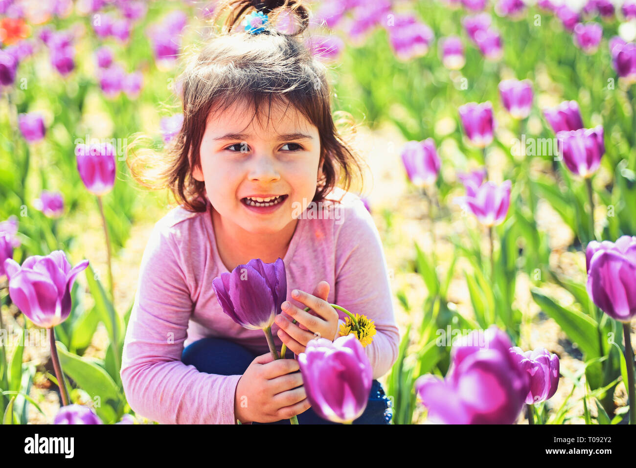 Frühling Schönheit. Kleines Mädchen im sonnigen Frühling. Sommer Mädchen Mode. Glückliche Kindheit. Gesicht Hautpflege. Allergie zu Blumen. Frühling Tulpen. Wetter Stockfoto