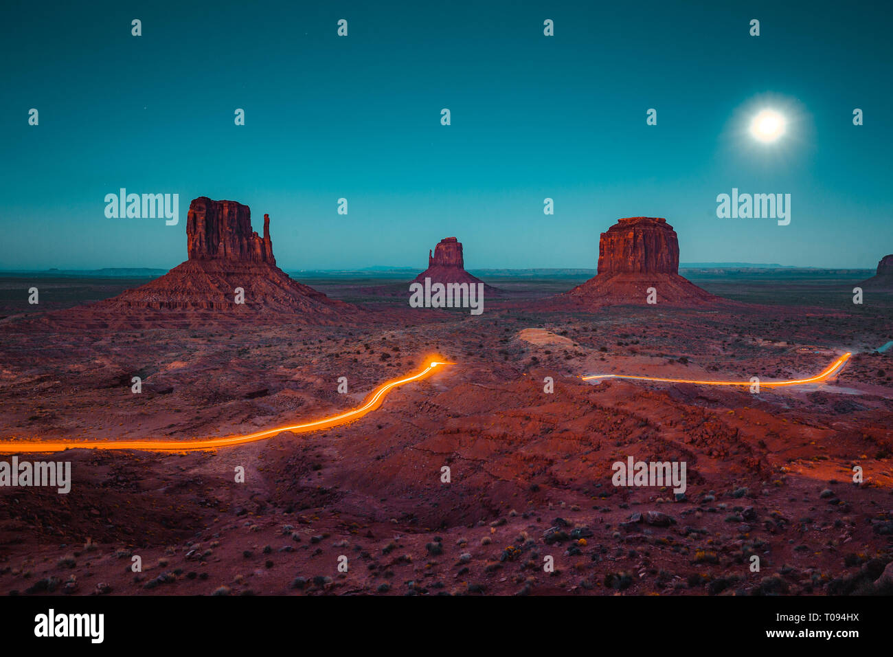 Klassische Panoramablick auf den malerischen Monument Valley mit dem berühmten Mittens und Merrick Butte mit Licht in der Nacht Spuren im Sommer, Arizona, USA Stockfoto