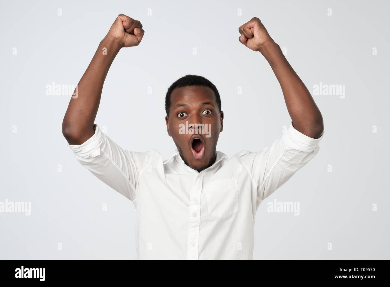 Sieger feiert. Aufgeregt afrikanischer Mann mit glücklichen Gesichtsausdruck holding Fäuste oben Stockfoto