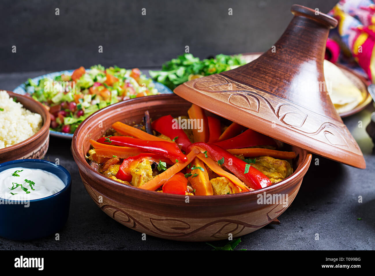 Marokkanisches Essen. Traditionelle tajine Gerichte, Couscous und frischen Salat auf rustikalen Holztisch. Tajine Hähnchen Fleisch und Gemüse. Arabische Küche. Stockfoto