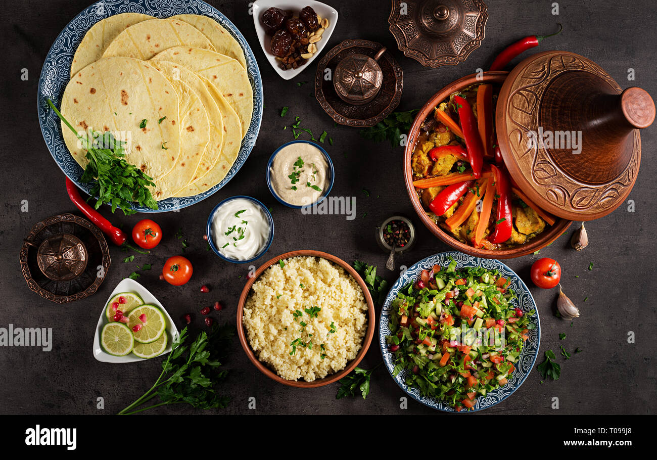 Marokkanisches Essen. Traditionelle tajine Gerichte, Couscous und frischen Salat auf rustikalen Holztisch. Tajine Hähnchen Fleisch und Gemüse. Arabische Küche. Top Stockfoto