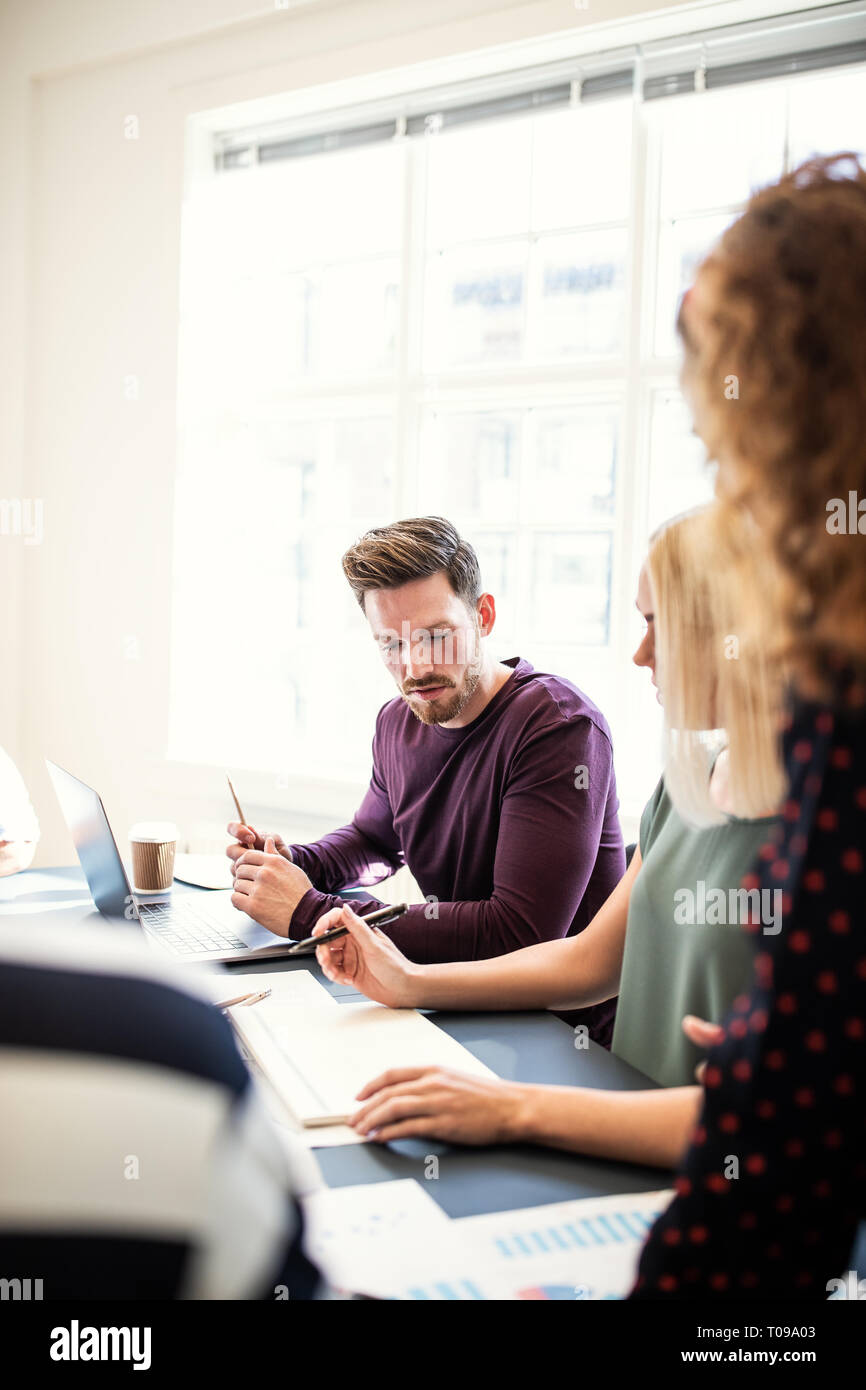 Gruppe junger Designer Schreibarbeit diskutieren zusammen sitzen um einen Konferenztisch in einem Büro Stockfoto