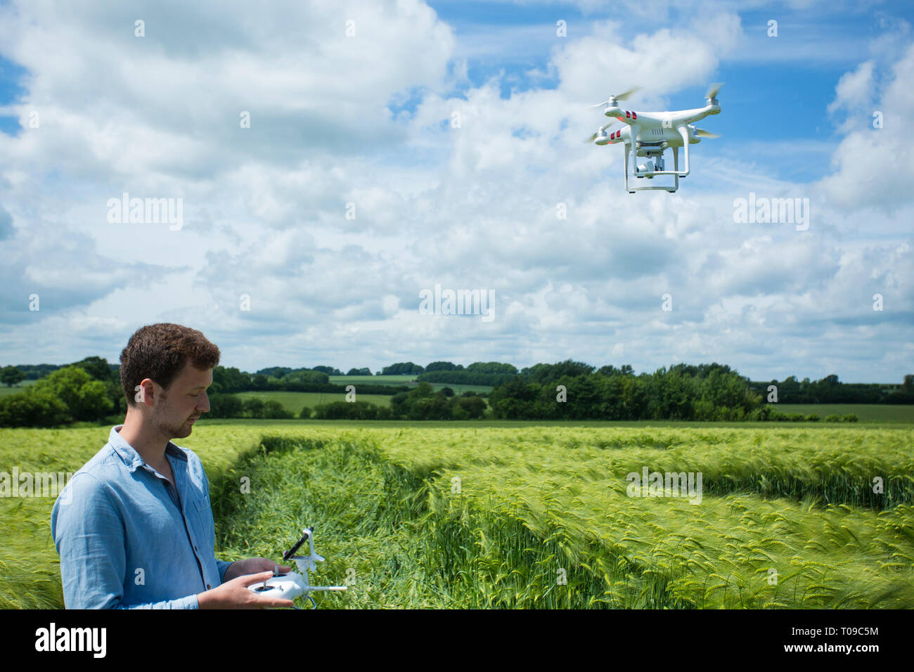 Grossbritannien, England, Wiltshire. Menschen, die eine Drohne in einem kornkreis. Stockfoto