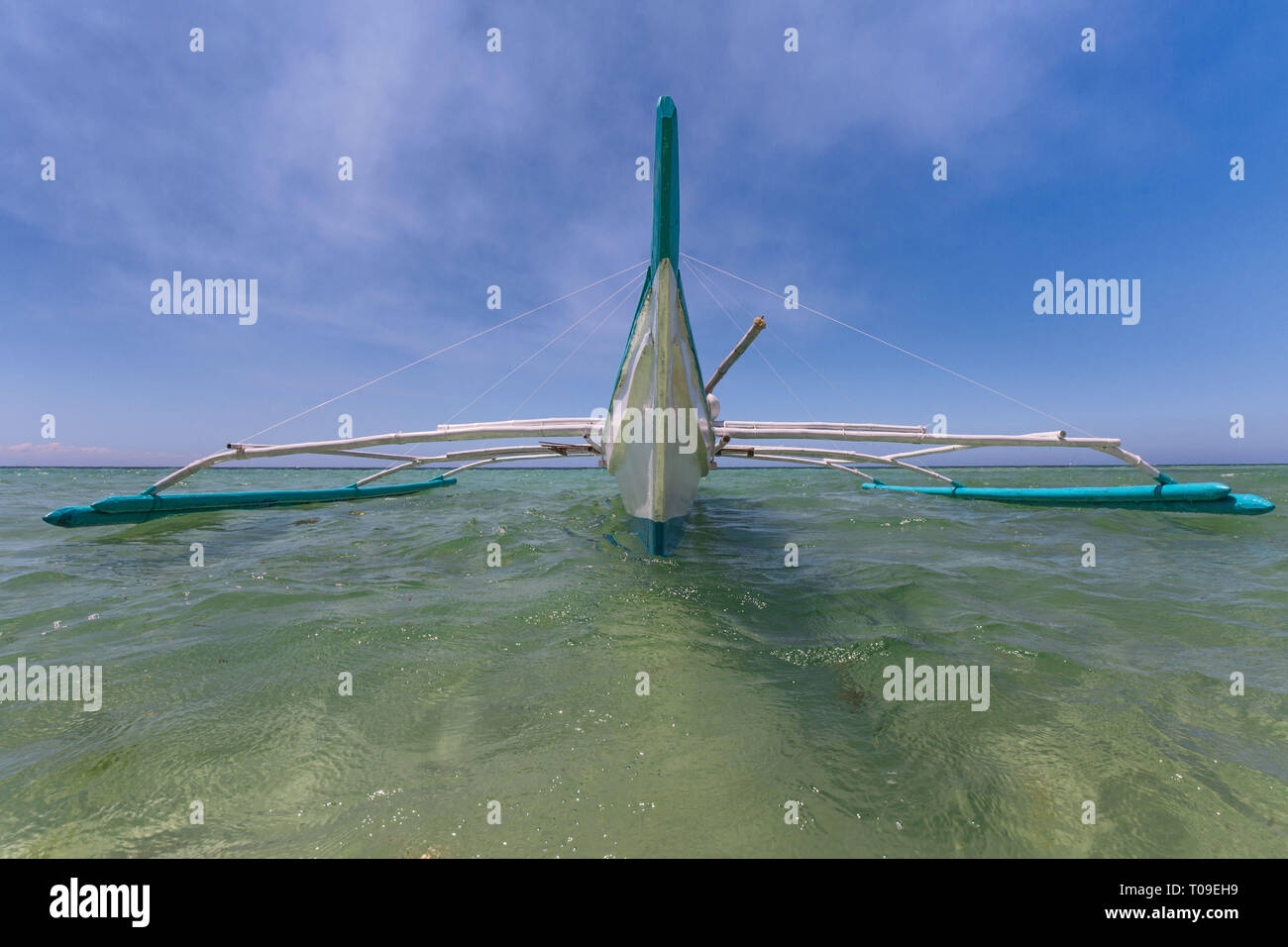 Outrigger pumpboat auf Wasser in Frontalansicht mit Weitwinkelobjektiv Perspektive mit blauem Himmel, weißen Wolken Hintergrund Stockfoto