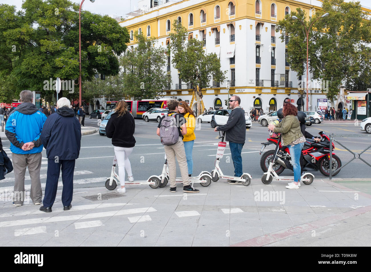 Gruppe von Touristen auf Mietwagen Motorroller an der Kreuzung in Sevilla, Spanien warten Stockfoto