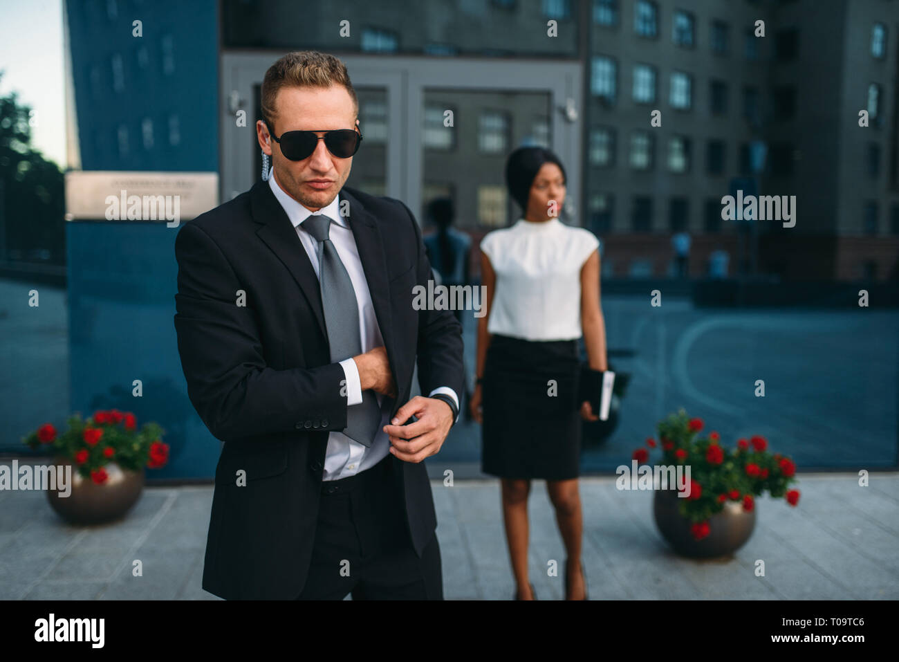 Leibwächter in Anzug und Sonnenbrille, weiblich VIP-Kunde für den Hintergrund. Security Guard ist eine riskante Beruf, professionelle Bewachung, business Personen Protein Stockfoto