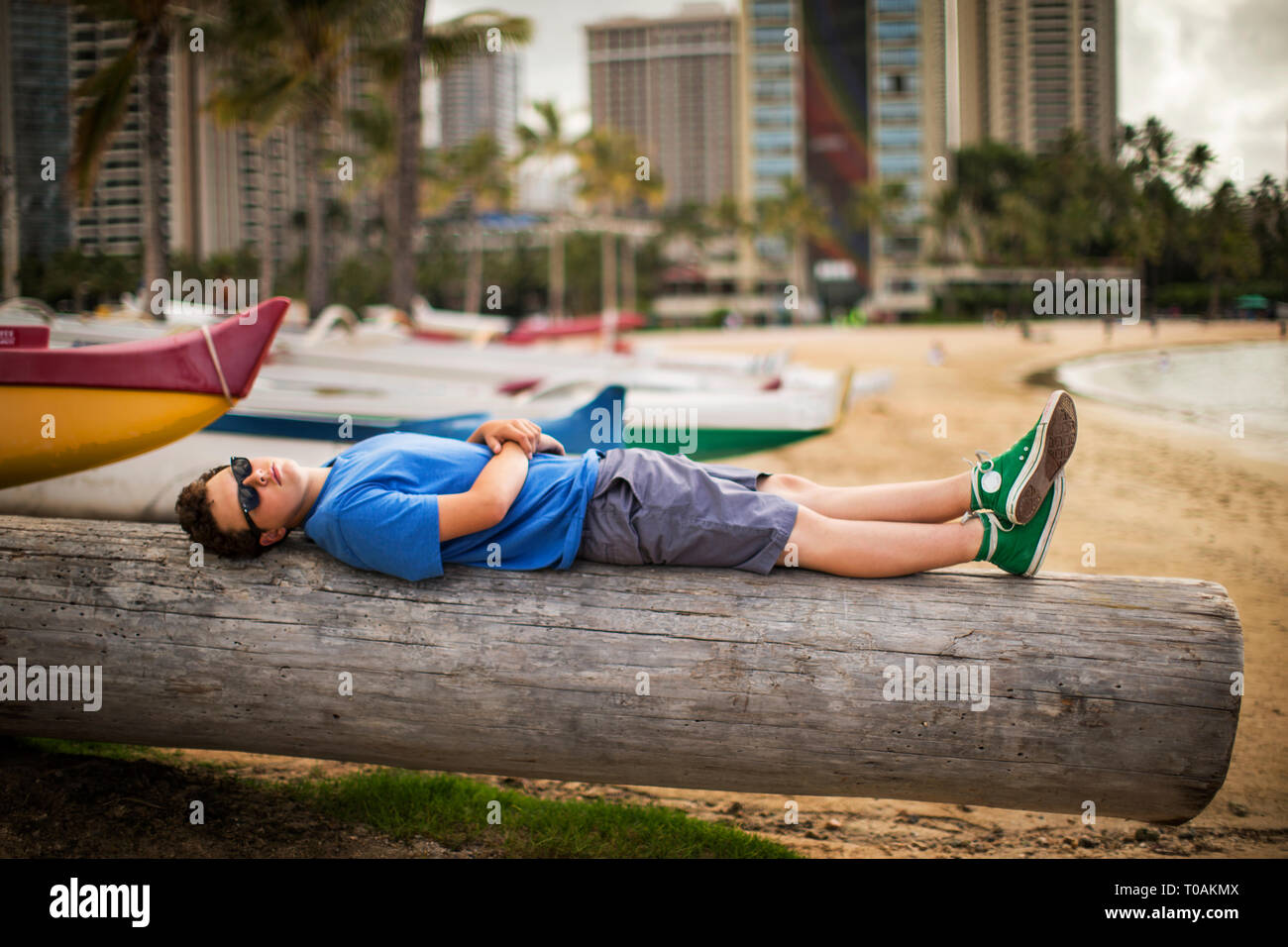 Teenager liegen auf einem Baumstamm auf einem Strand. Stockfoto