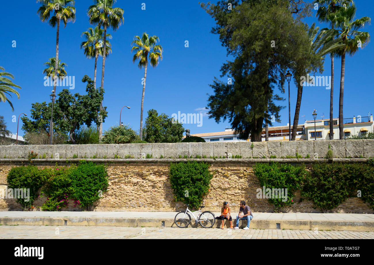 Ein junges Paar mit einem Fahrrad sprechen neben dem Fluss Guadalquivir in Sevilla Stockfoto