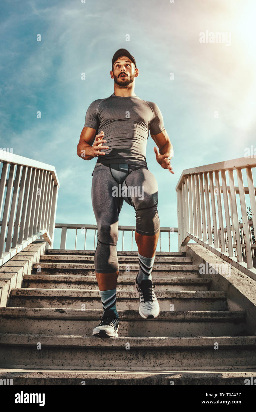 Junge muskulöse Sportler ist die Treppe an der Brücke. Stockfoto