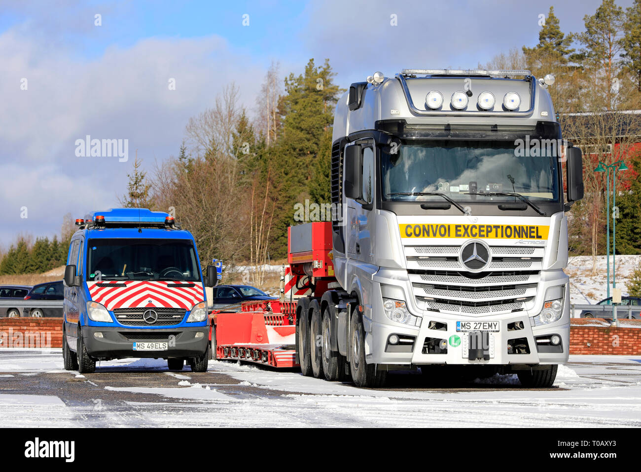 Salo, Finnland - 9. März, 2019: Silber Mercedes-Benz Actros 4163 Lkw und Trailer für Heavy duty Oversize load Transport mit Pilot Fahrzeug geparkt. Stockfoto