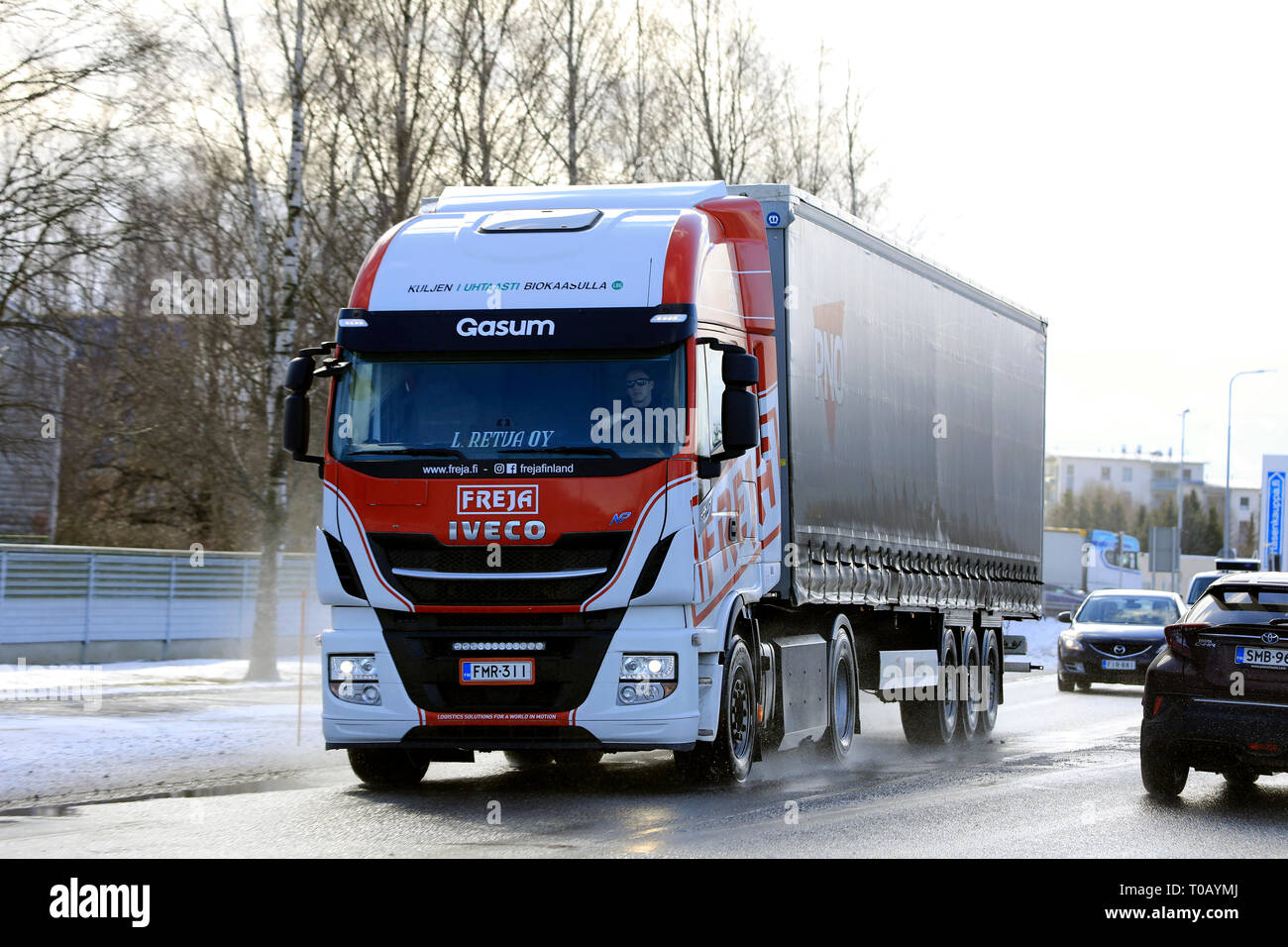 Salo, Finnland - 9. März 2019: Biogas betrieben Iveco Stralis NP LKW L. Retva Oy zieht Anhänger auf nasser Straße unter den Verkehr am Tag des frühen Frühling. Stockfoto