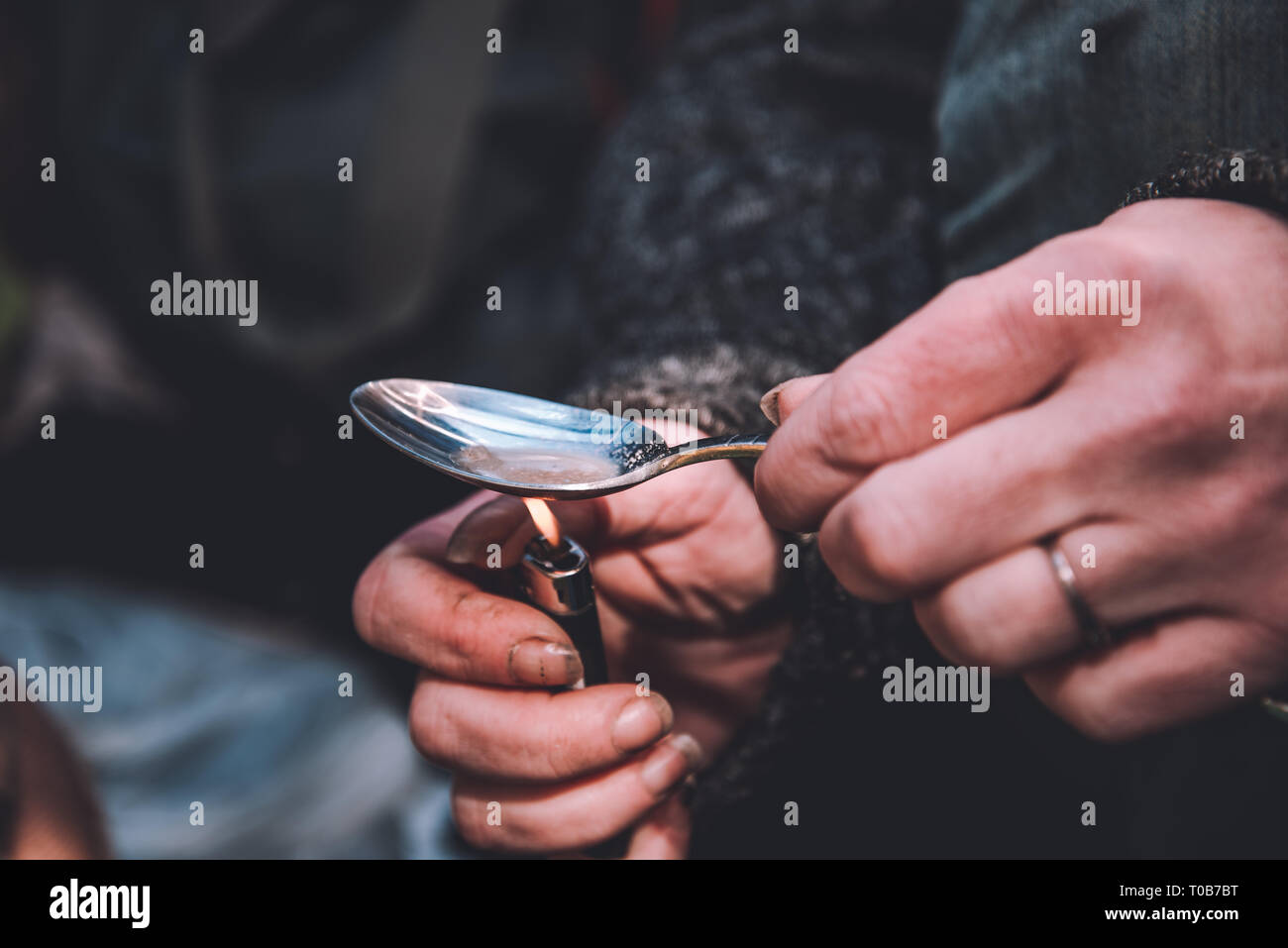 Eine obdachlose Frau Süchtiger heizt Heroin in einem Löffel. Stockfoto