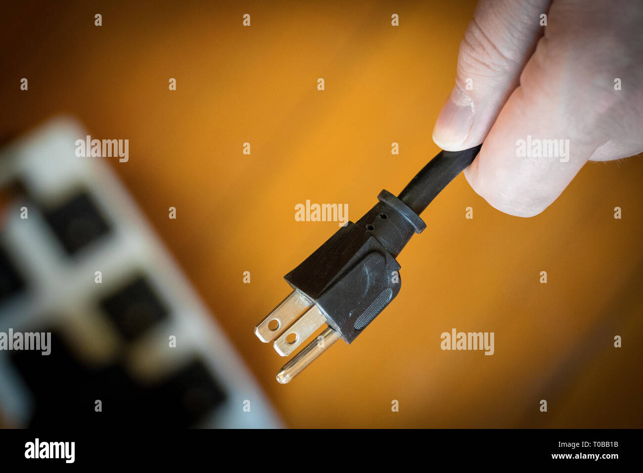 Geerdete elektrische Kabel in der Hand, bereit zum Stopfen von der Stromversorgung trennen. Stockfoto