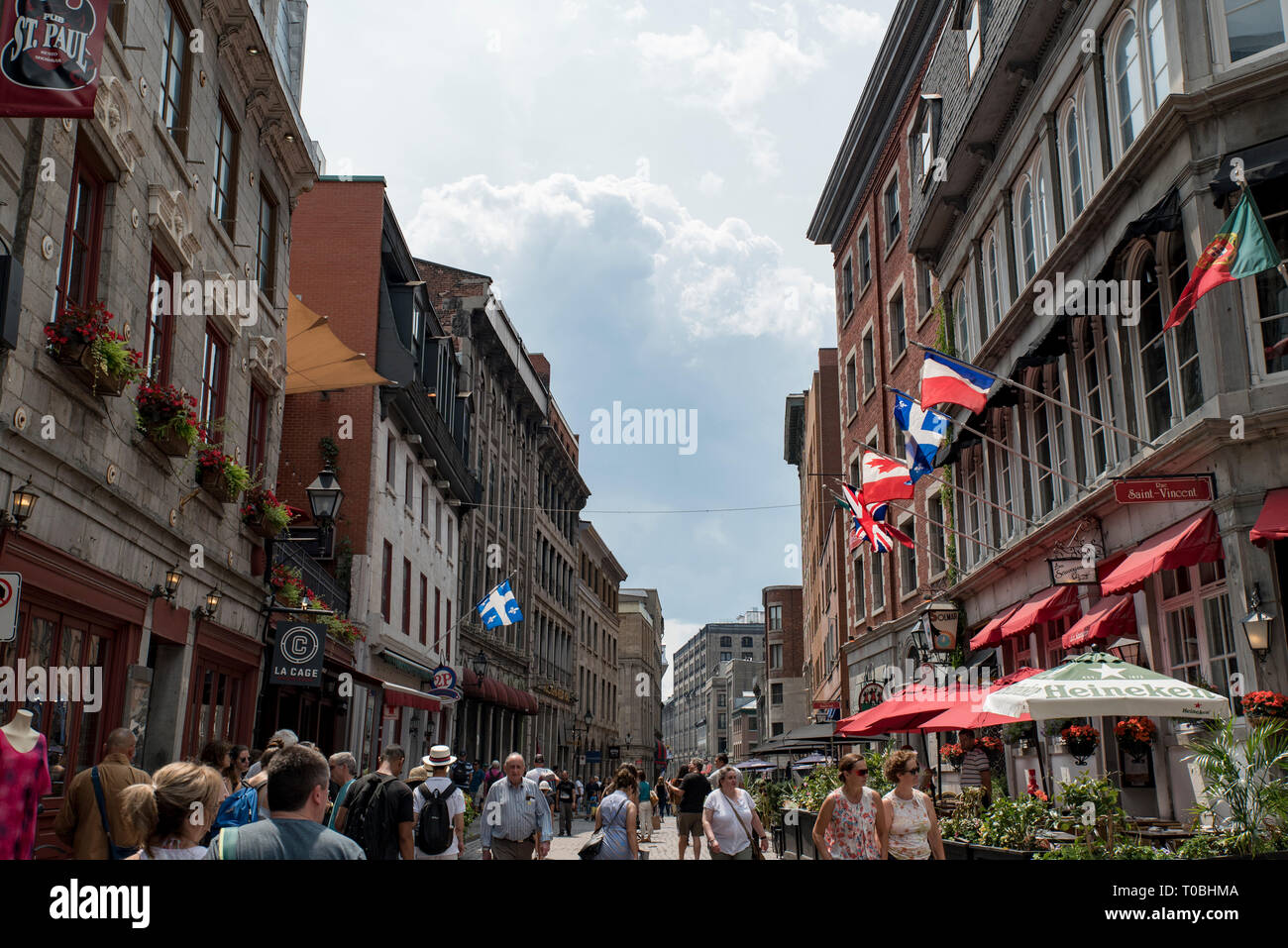 Montreal, Quebec, Kanada. Blick nach Westen, Saint Paul Street East at Saint Vincent Street an Menschen und Häuser mit Fahnen in der Altstadt von Montreal. Stockfoto