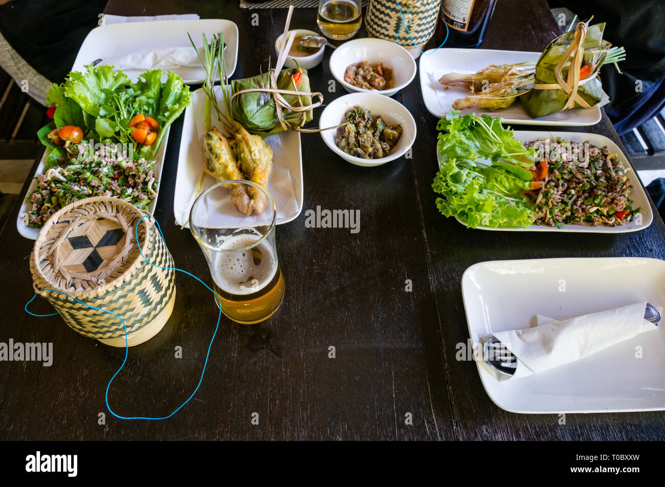 SE asiatischen Lao Gerichte auf Mittagstisch mit Reis gefüllte Körbe Zitronengras und Saucen im Tamarind Kochschule, Luang Prabang, Laos Stockfoto
