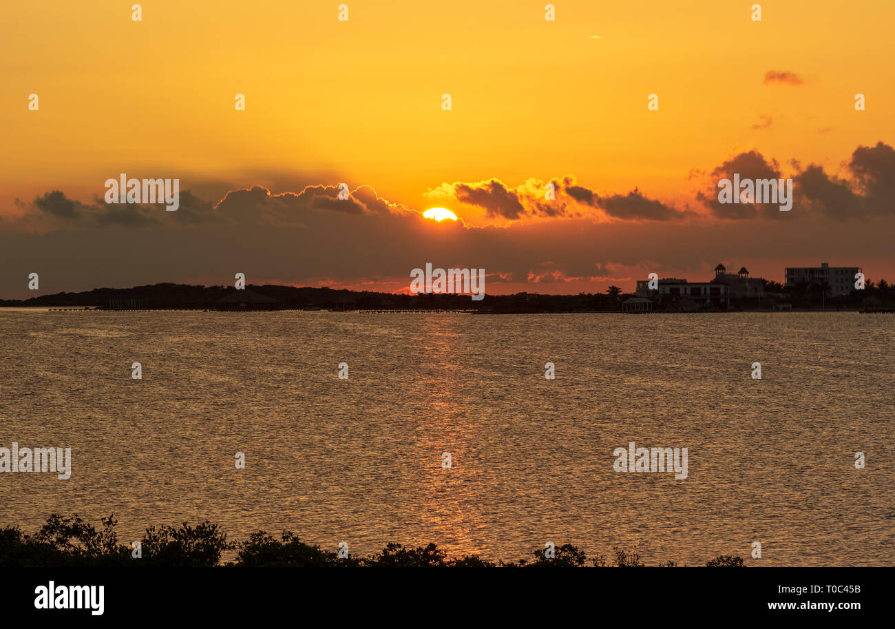 Die Sonne über Chetumal Bay vor Ambergris Caye, Belize casting brillante Farbtöne über den Himmel und in den Gewässern durch eine warme Brise gekräuselte Wellen reflektiert. Stockfoto