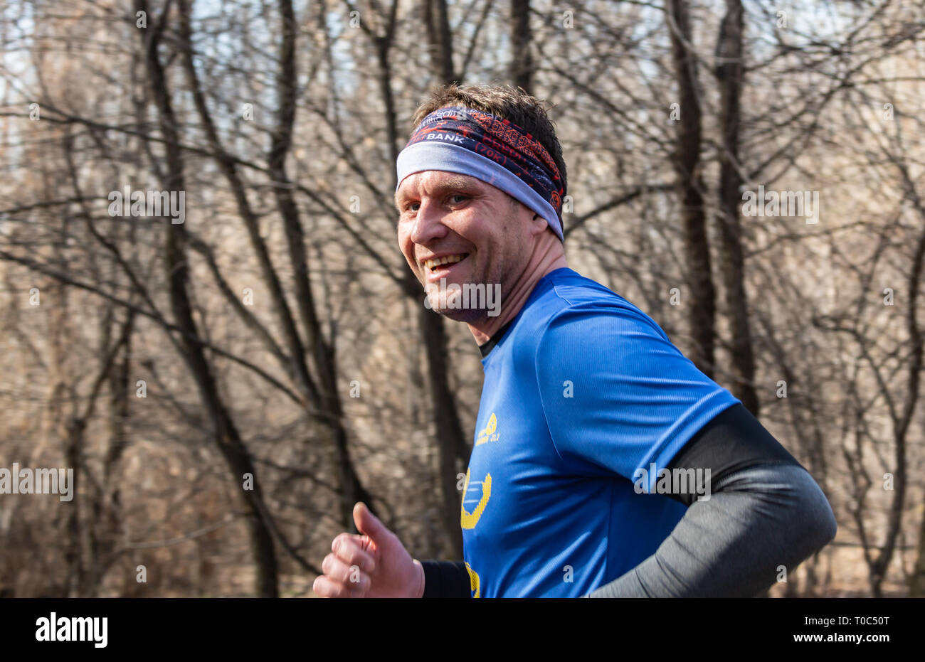 ALMATY, Kasachstan - 16. März 2019: Porträt einer stattlichen Reifen unbekannter Mann, der durch die Wälder im Frühjahr beim Marathon in der Stadt läuft Stockfoto