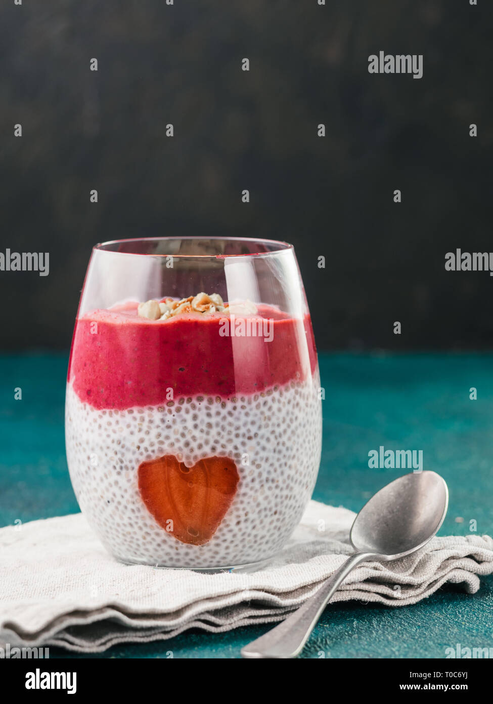 Idee für gesundes Frühstück am Valentinstag: Chia Pudding mit roten Beeren Püree, gehackte Mandeln auf und Erdbeere in der Form des Herzens. Kopieren Sie Platz für Text Stockfoto