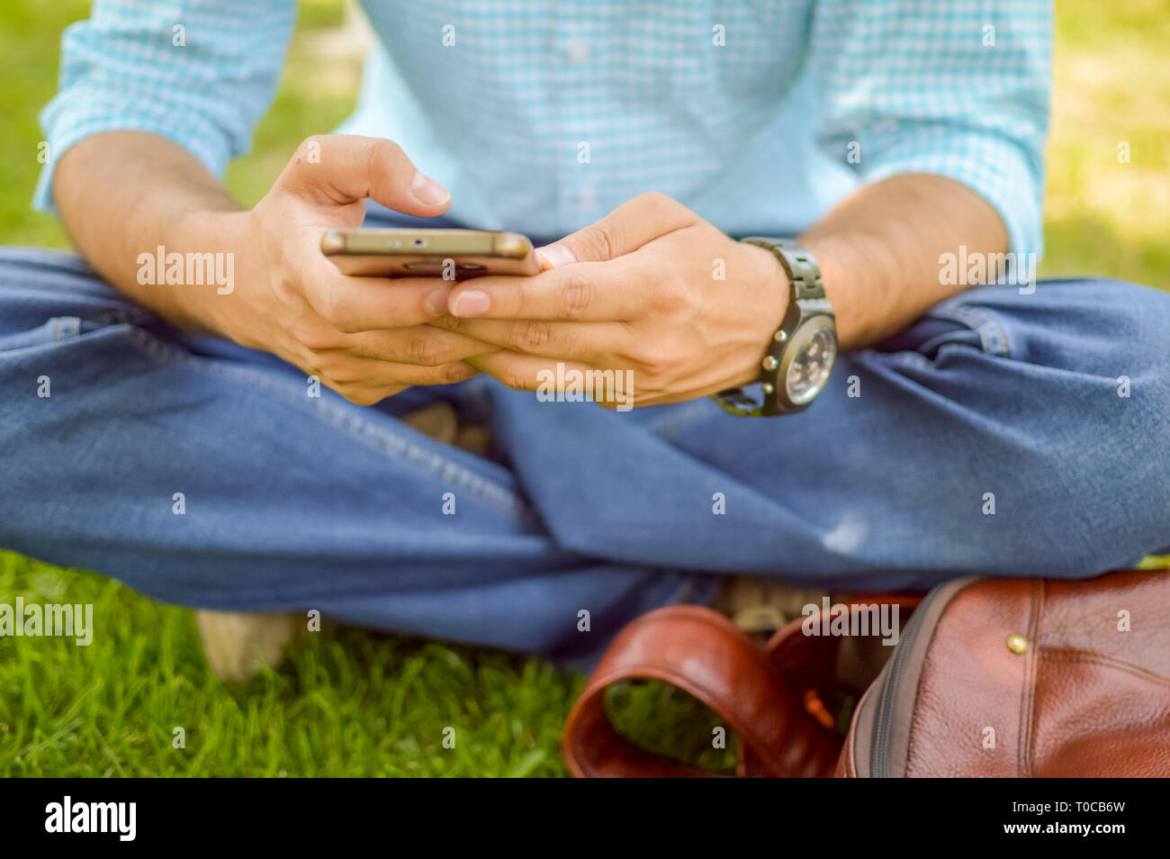 Eine Person mit seinem Handy und dabei einige Arbeit in einer Wiese oder Garten. Stockfoto