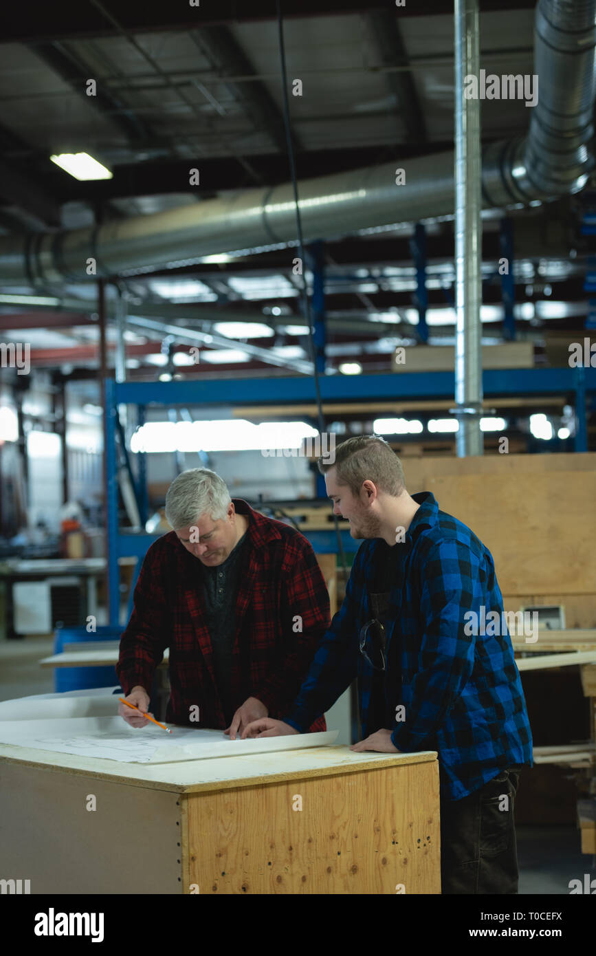 Kaukasier männliche Tischler diskutieren und Messung in der Werkstatt Stockfoto