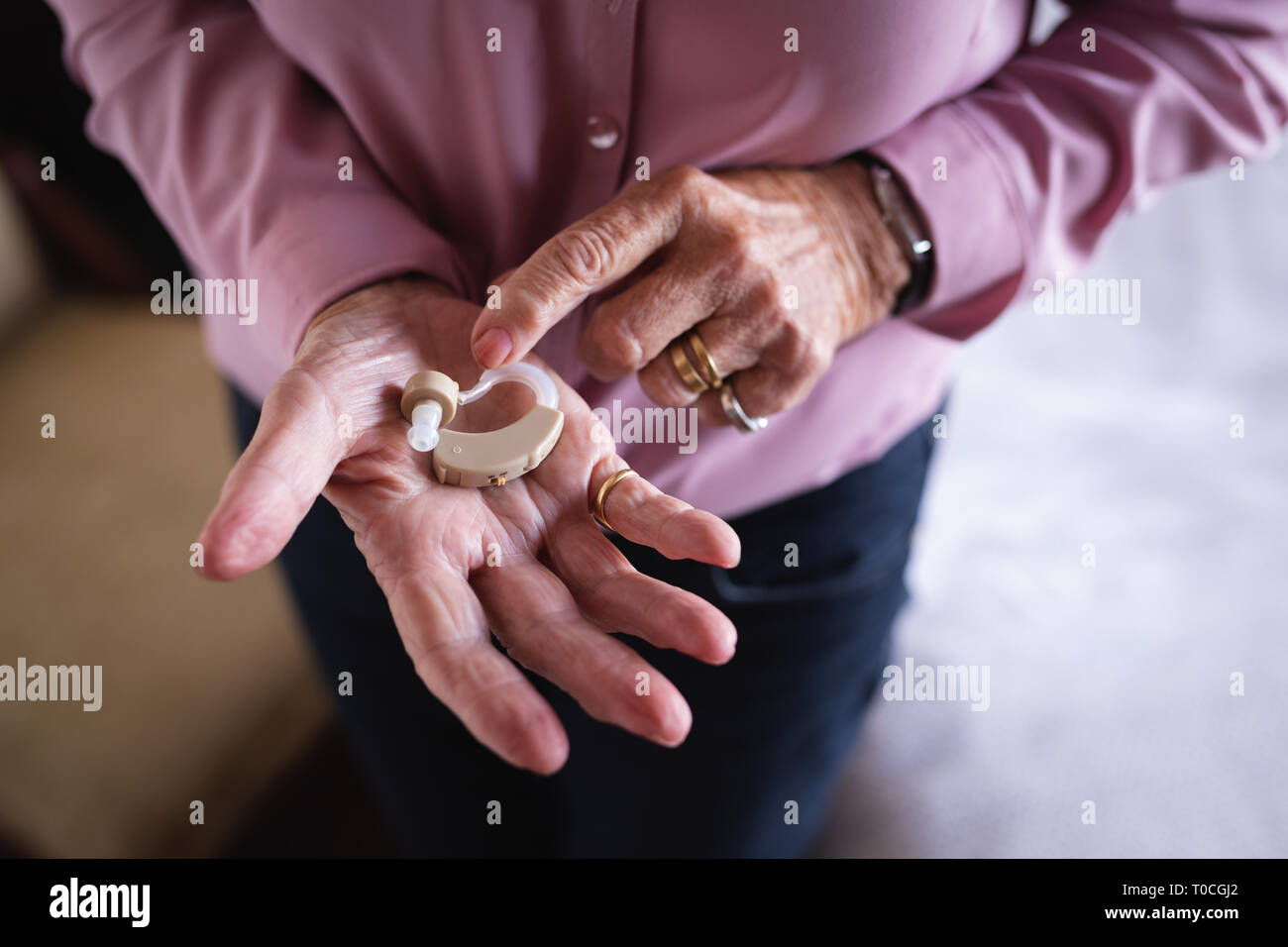 Active Senior woman holding Hörgerät in der Hand zu Hause Stockfoto