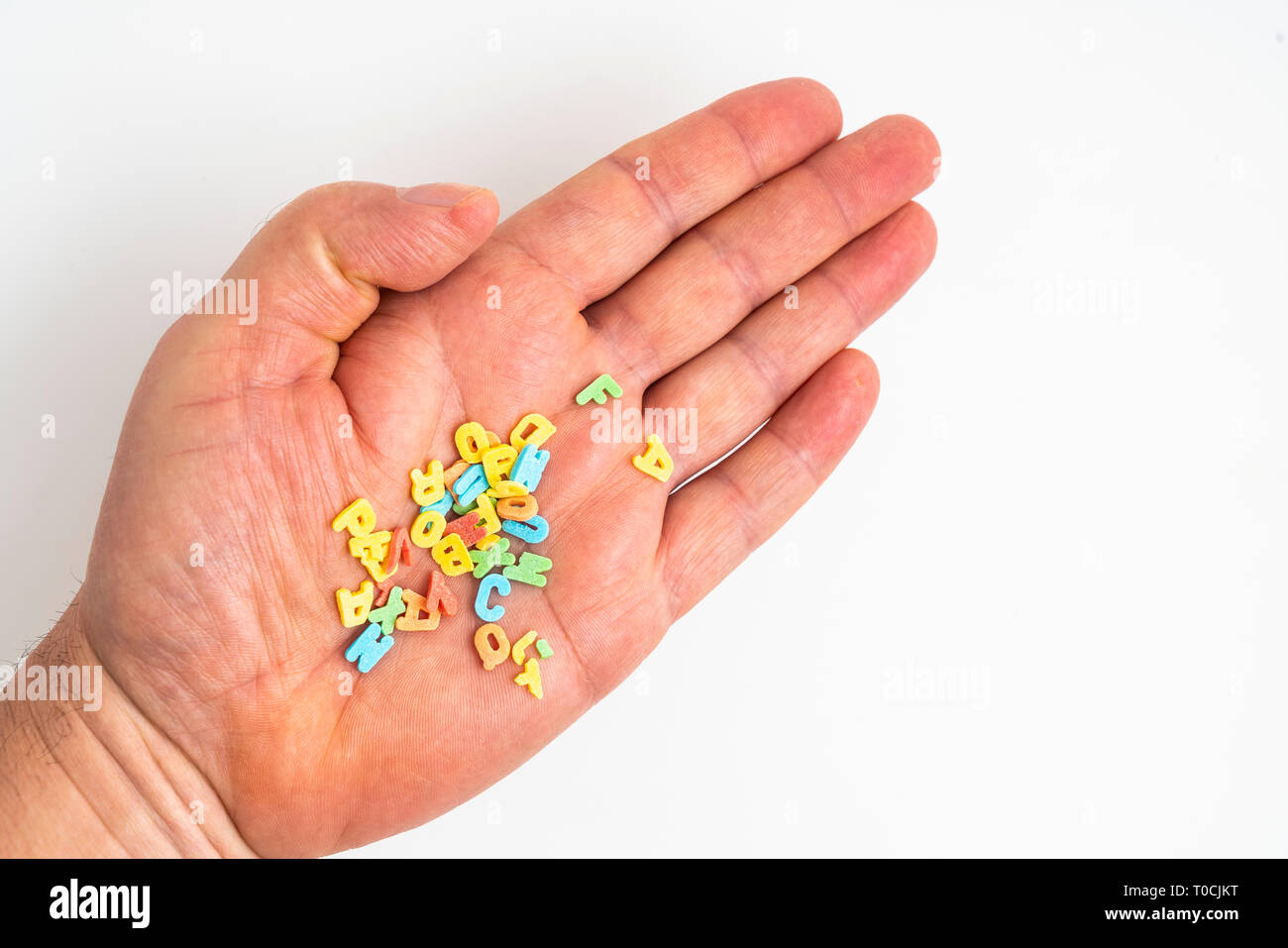 Die bunten Buchstaben, die in der Palme einer Hand verstreut Stockfoto