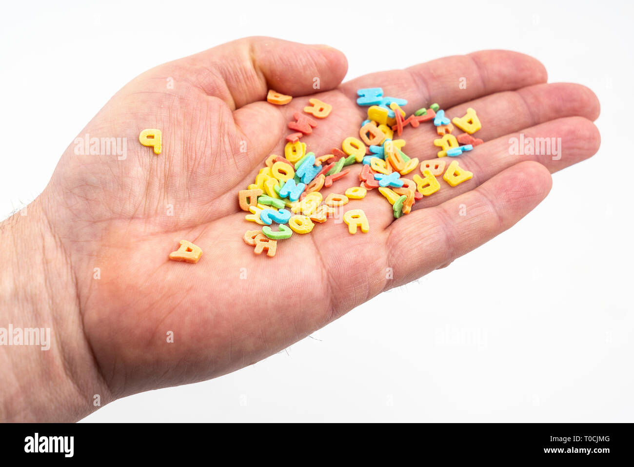 Die bunten Buchstaben, die in der Palme einer Hand verstreut Stockfoto
