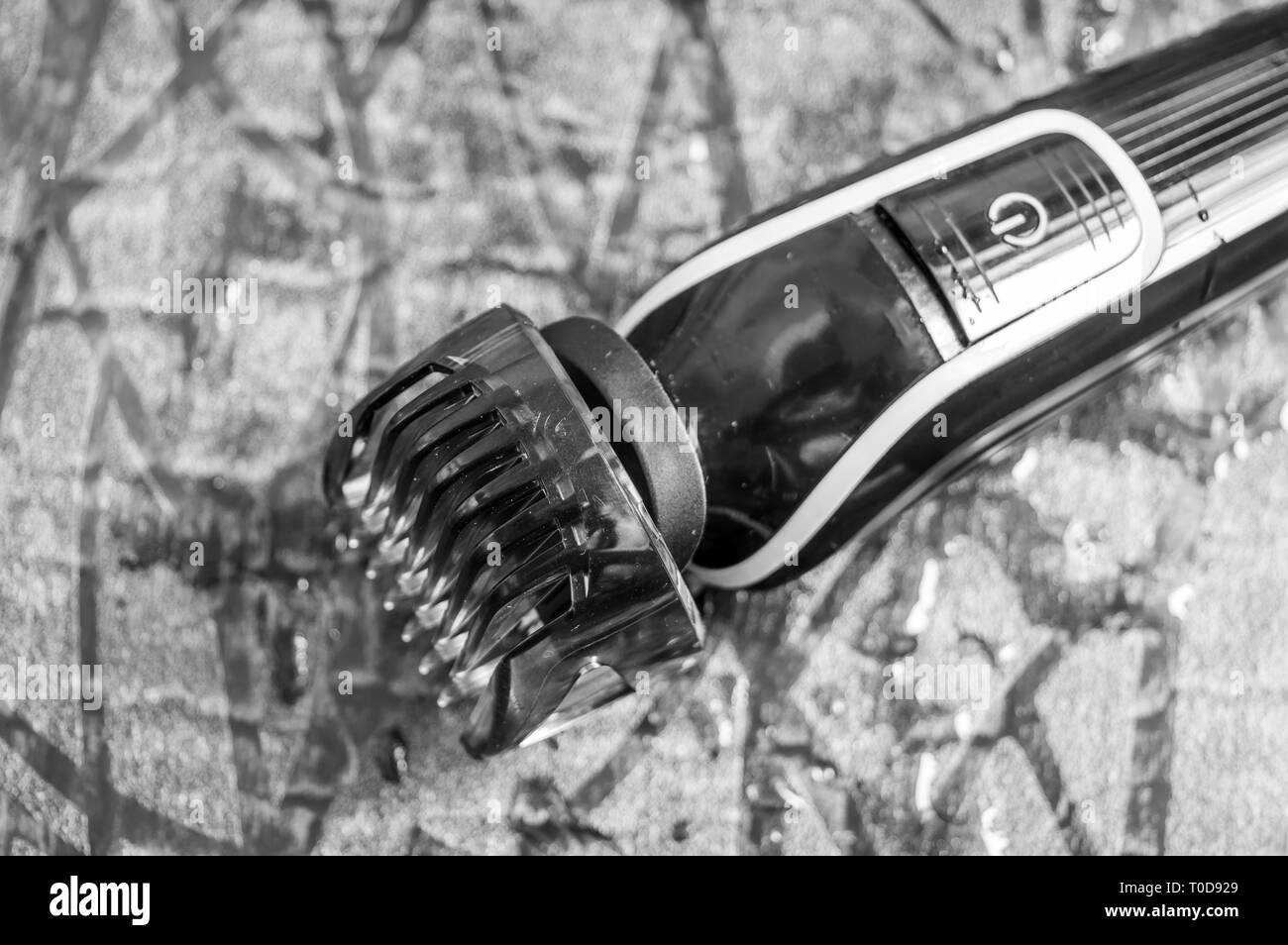 Elektrischer Rasierapparat des Menschen oder Fräser mit einer Einstellung Blade comb gehalten auf einer nassen Boden Stockfoto