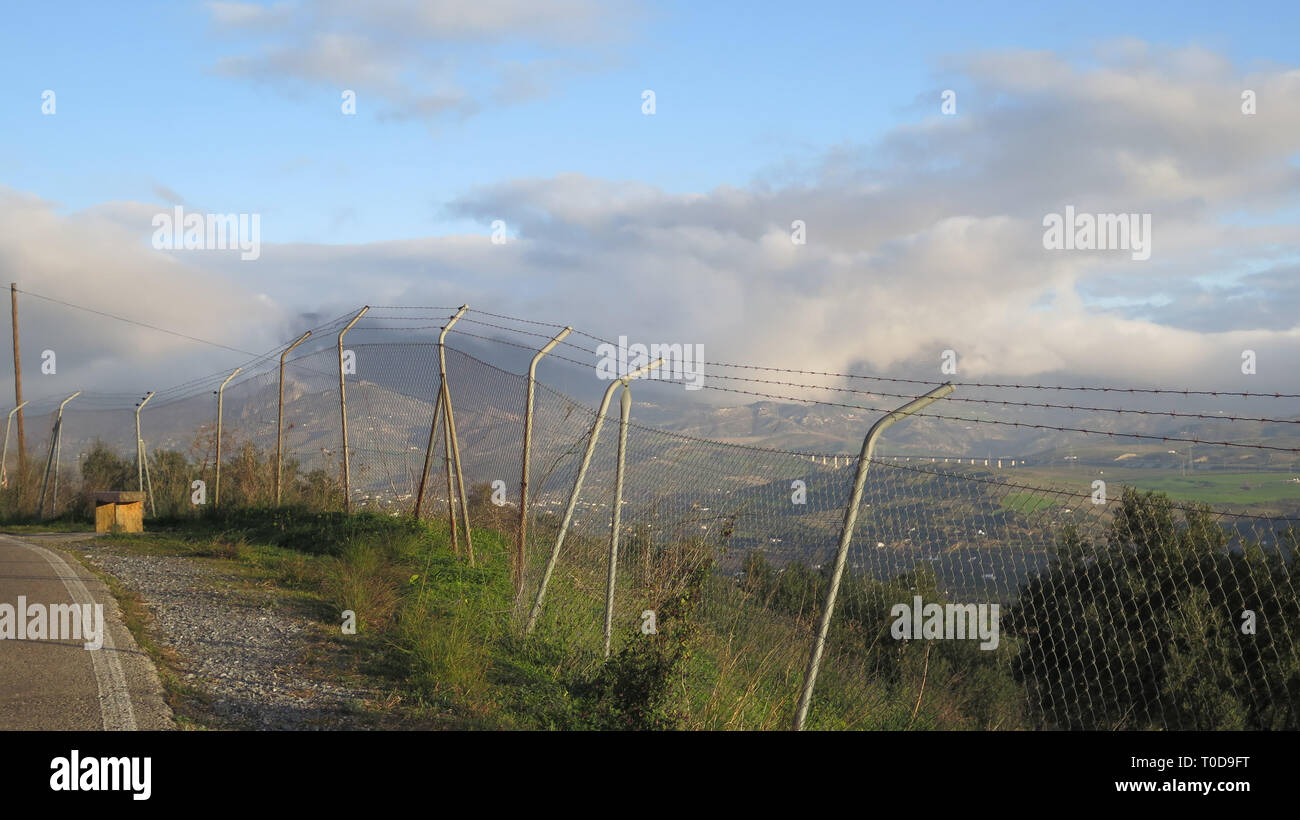 Blick auf das Tal durch den Maschendrahtzaun mit Reihen von Stacheldraht in Andalusien gekrönt Stockfoto