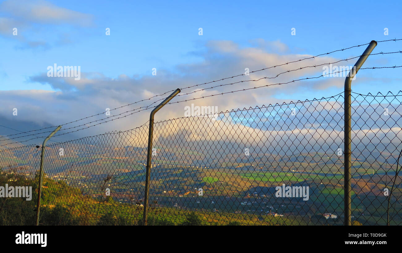 Blick auf das Tal durch den Maschendrahtzaun mit Reihen von Stacheldraht in Andalusien gekrönt Stockfoto