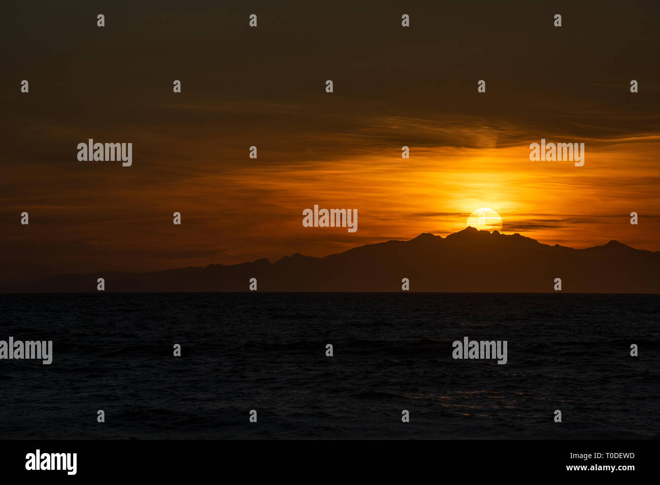 Die Sonne geht hinter die italienische Insel Elba vor der toskanischen Küste im Mittelmeer. Stockfoto