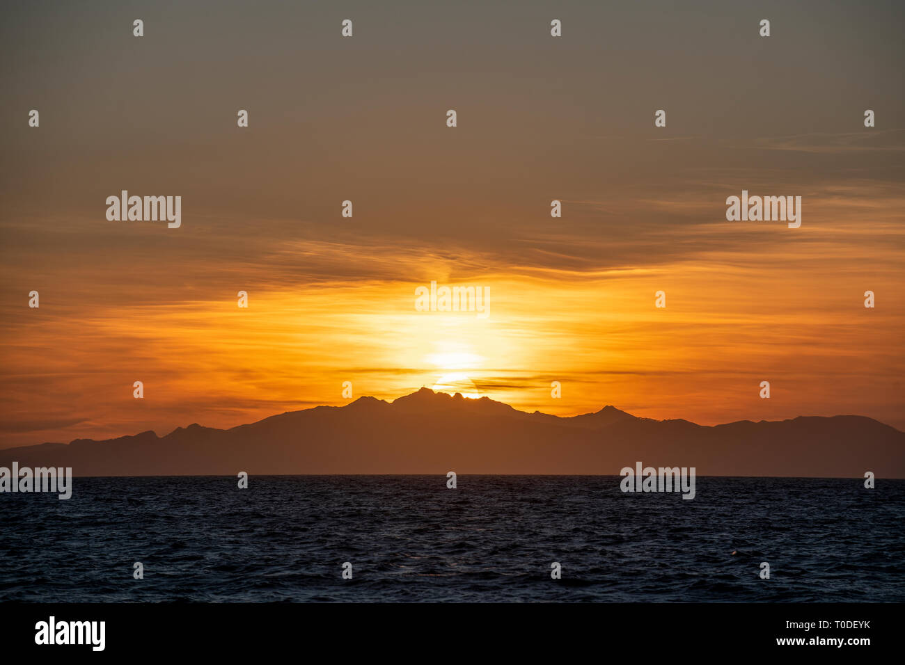 Die Sonne geht hinter die italienische Insel Elba vor der toskanischen Küste im Mittelmeer. Stockfoto