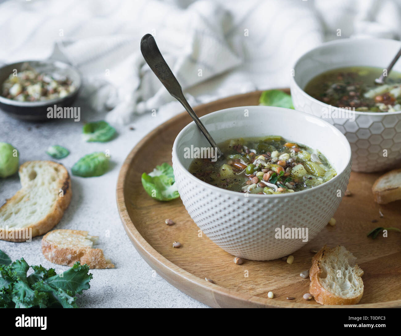 Grünes Gemüse vegane Suppe von Keil, Rosenkohl, Zucchini, Lauch mit verschiedenen gekeimten Samen und Sprossen mit Croutons auf Holz Tablett auf leichte b Stockfoto
