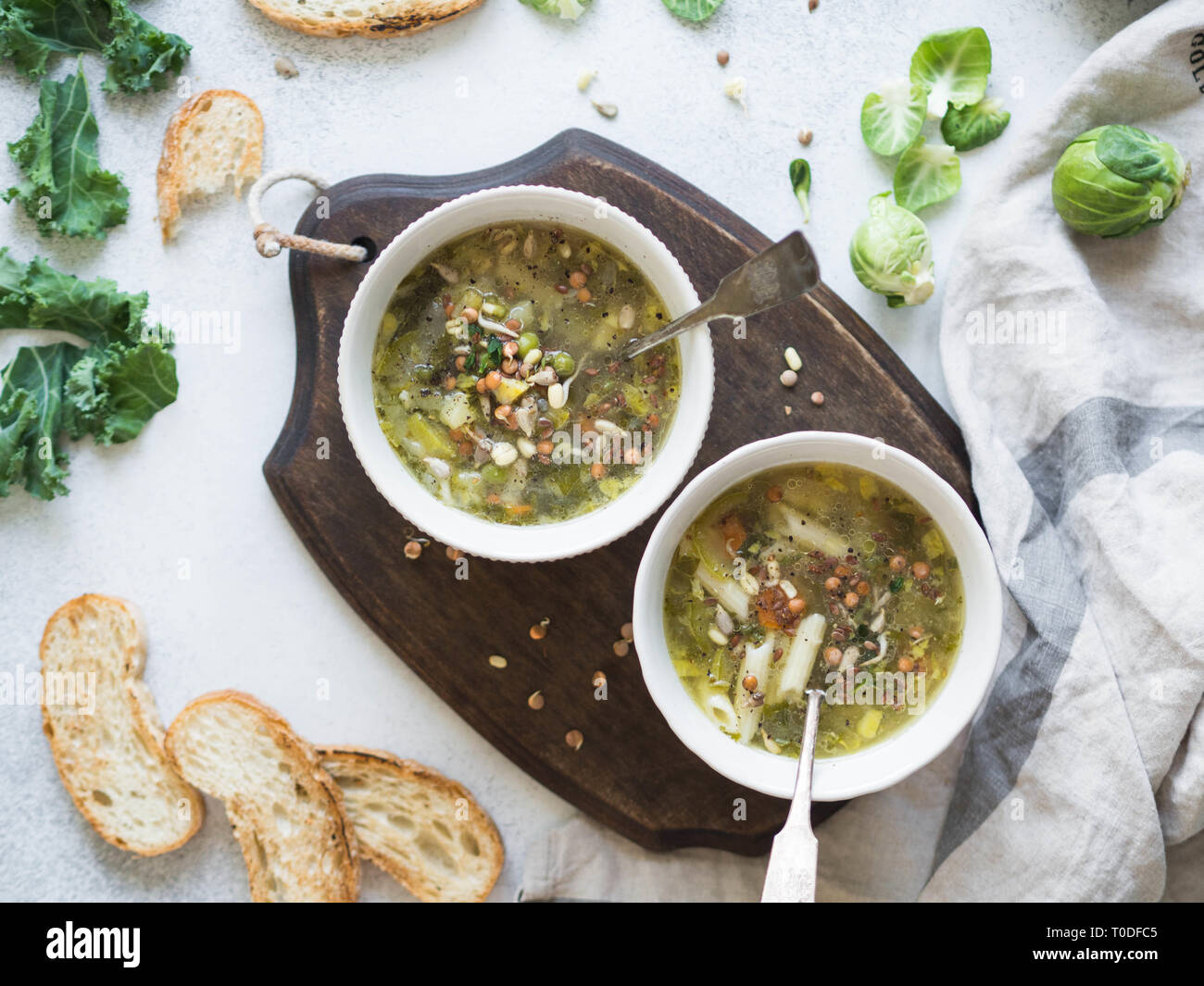 Grünes Gemüse vegane Suppe von Keil, Rosenkohl, Zucchini, Lauch mit verschiedenen gekeimten Samen und Sprossen mit Croutons auf Holz. Stockfoto