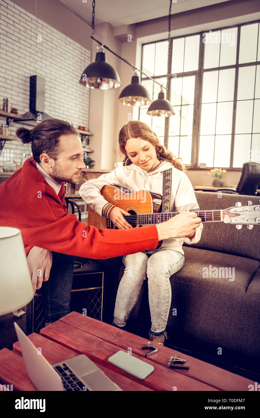 Mädchen mit sweatshirt Gefühl freudiger lernen Gitarre zu spielen. Stockfoto