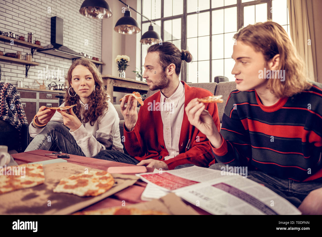 Unternehmen der drei jungen Musiker essen lecker Pizza zum Mittagessen Stockfoto
