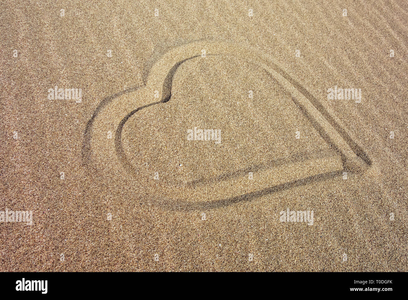 Herz am Sandstrand an der Küste gezogen Stockfoto
