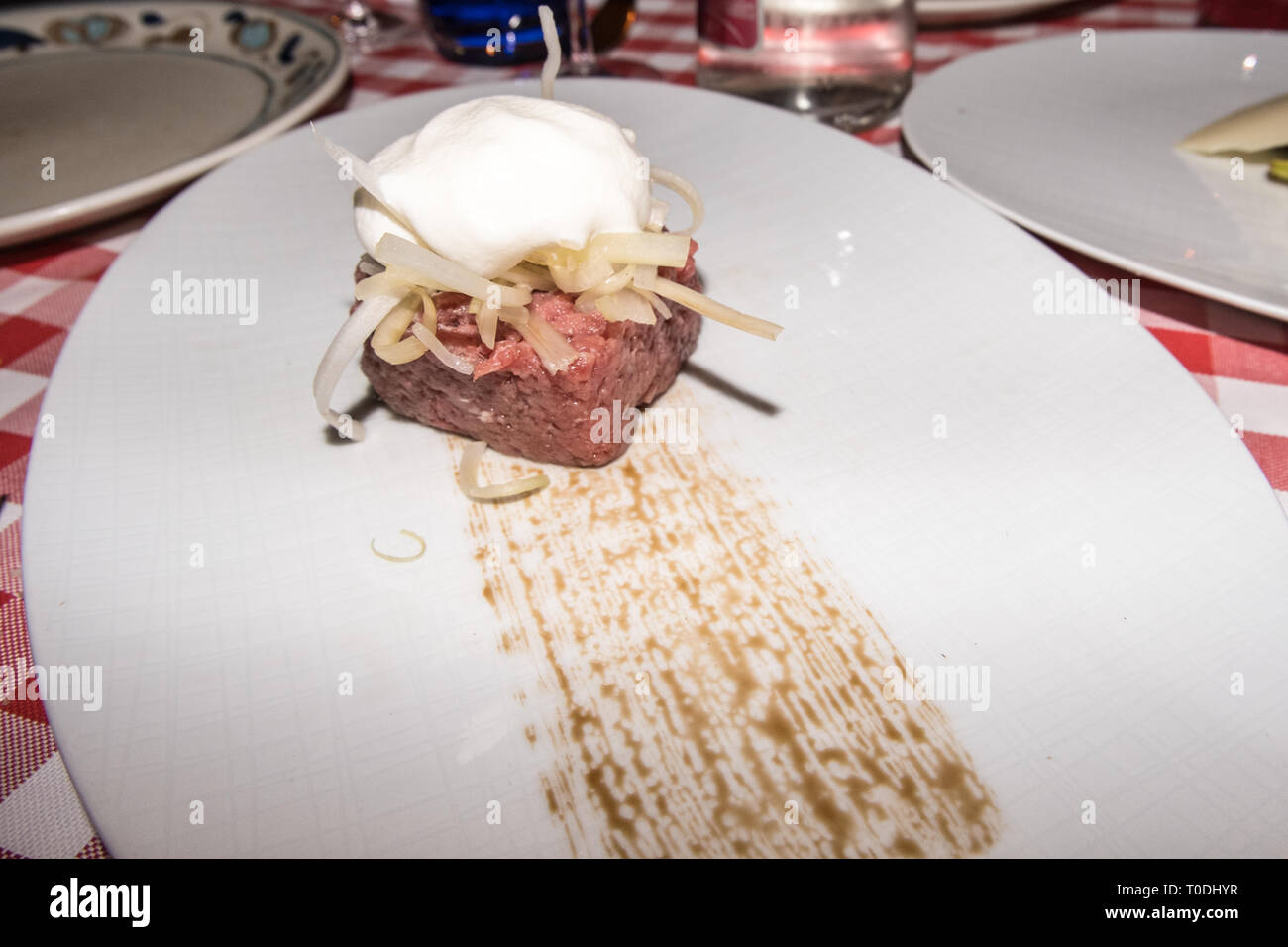 Gischt von 30 Monat gewürzt Parmesan auf knackige Sellerie auf einem handcut rohes Hackfleisch/Faschiertem Stockfoto