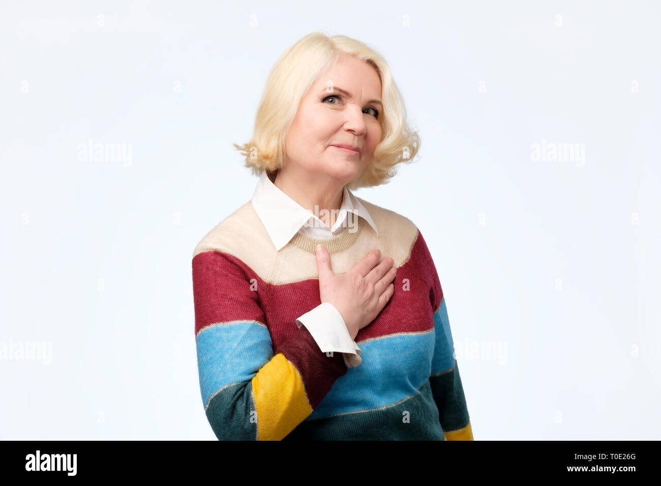 Schöne ältere Frau mit farbigen Pullover ist mit Kompliment berührt Stockfoto