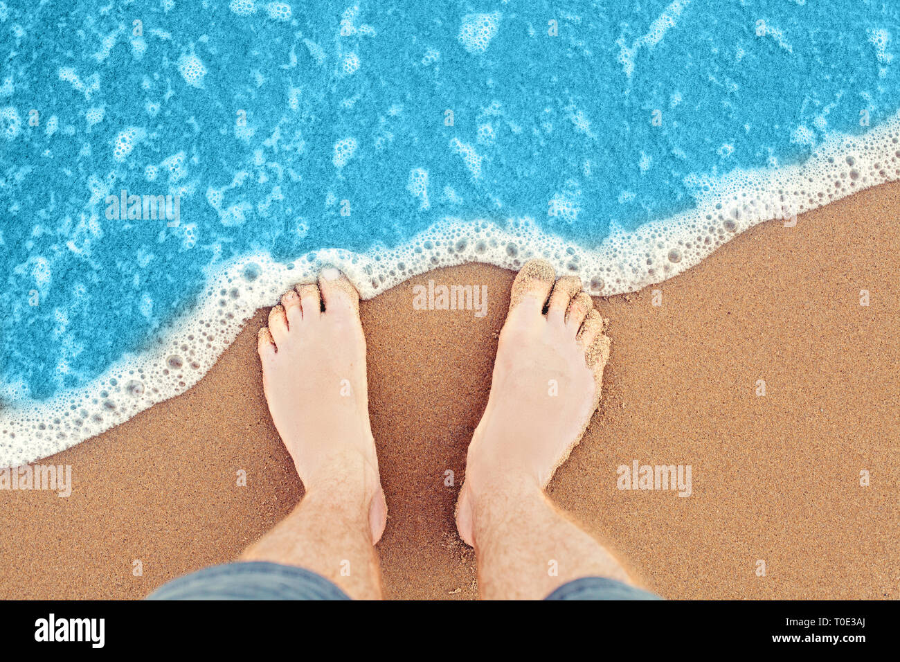 Füße Strand, Meer Hintergrund. Männliche Füße im Sand, Ansicht von oben Stockfoto