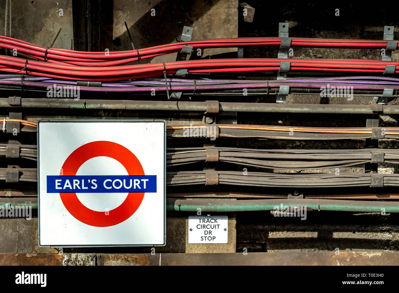 Parallel verlaufende elektrische Kabel und Kabel an der Wand der U-Bahnstation Earl's Court, London, Großbritannien Stockfoto