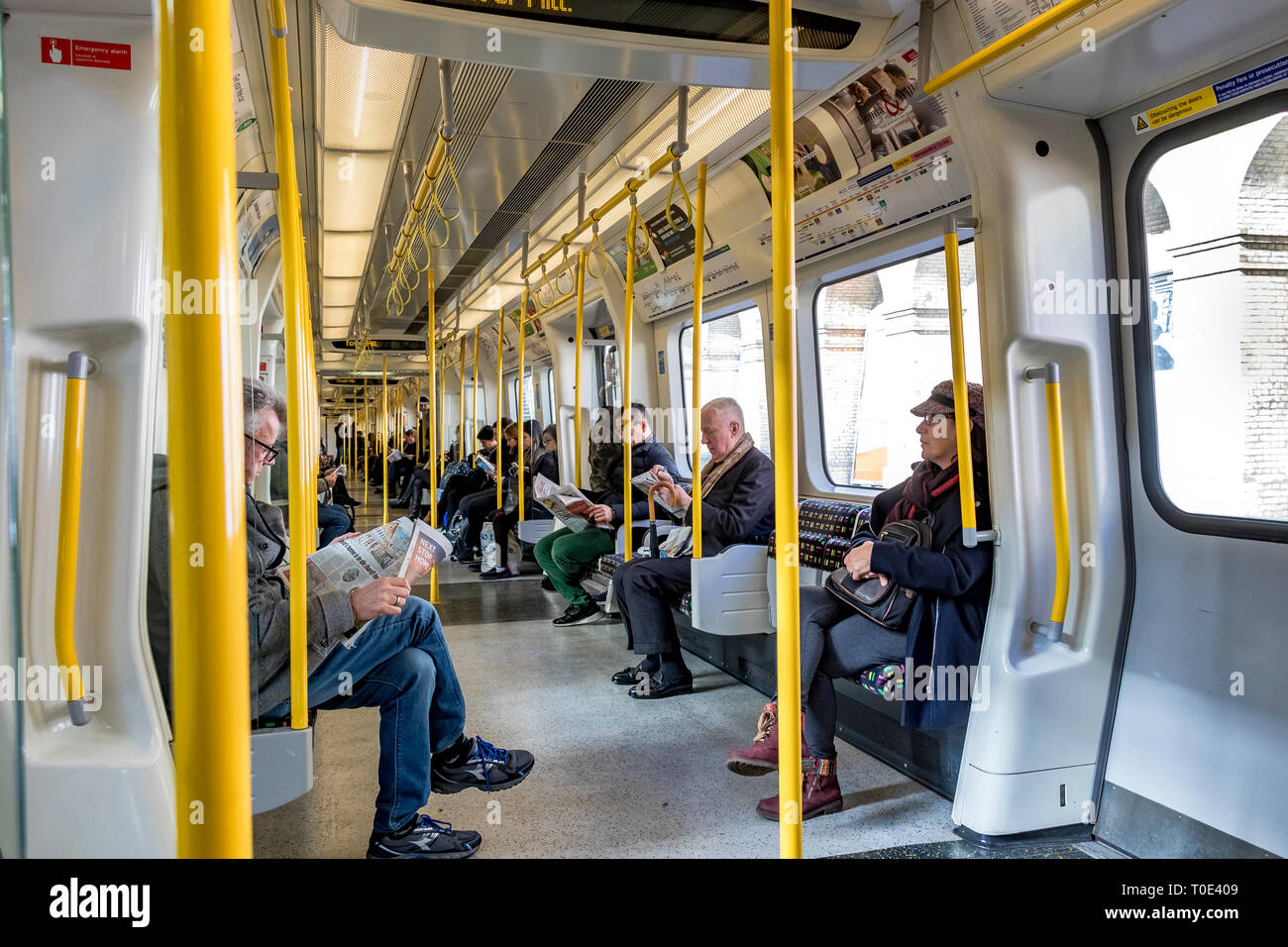 Personen, die auf einem Zug der S7 Stock District Line in der Londoner U-Bahn, London, Großbritannien, sitzen und stehen Stockfoto