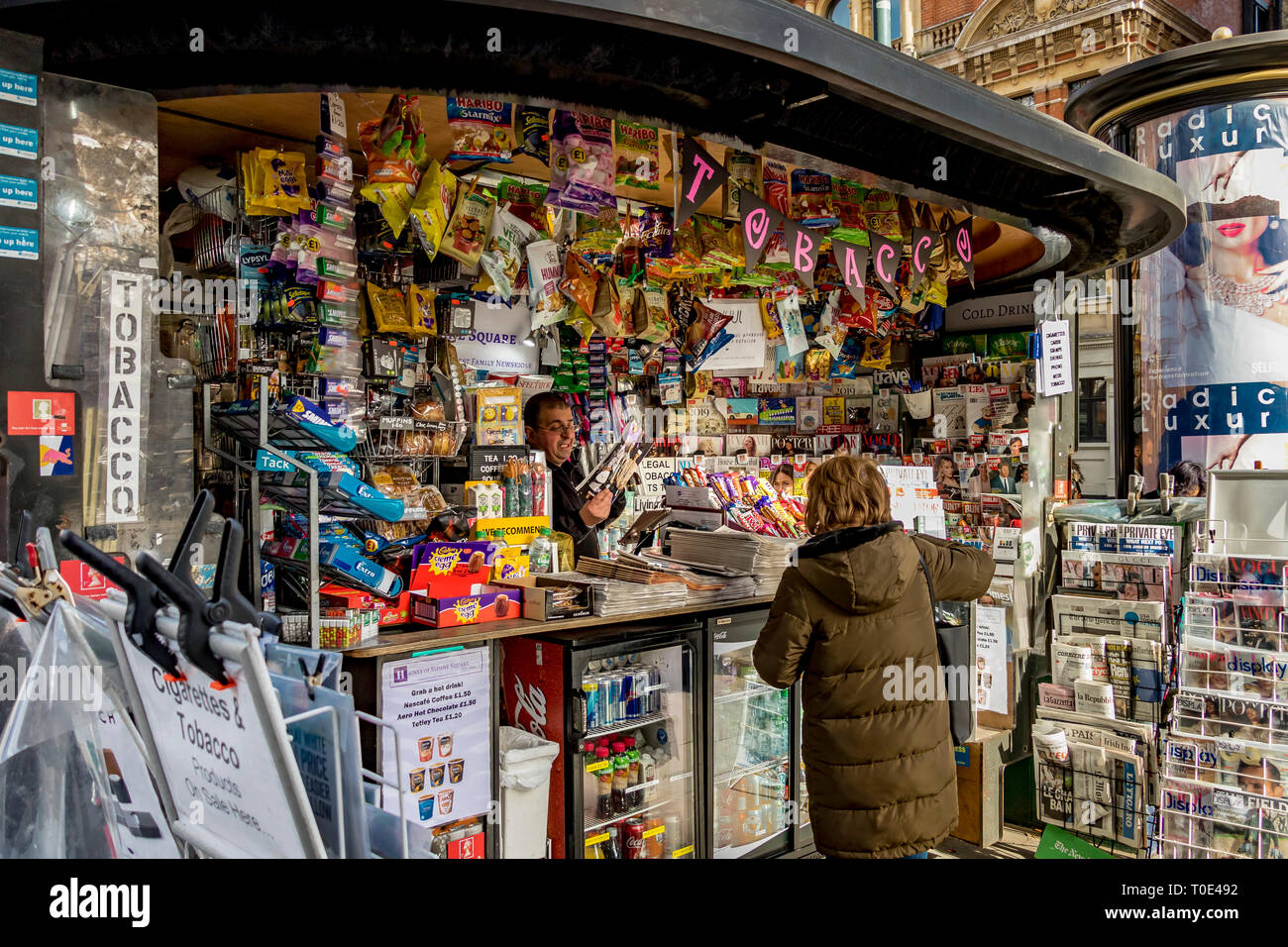 Eine Dame, die ein Magazin an einem Zeitungskiosks und Tabakkiosks vor der U-Bahn-Station Sloane Square, London, Großbritannien, kauft Stockfoto